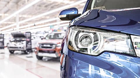 Close up of a blue car's headlight, with a car showroom as the background