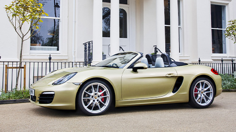 Gold Porsche Boxster, parked with roof down